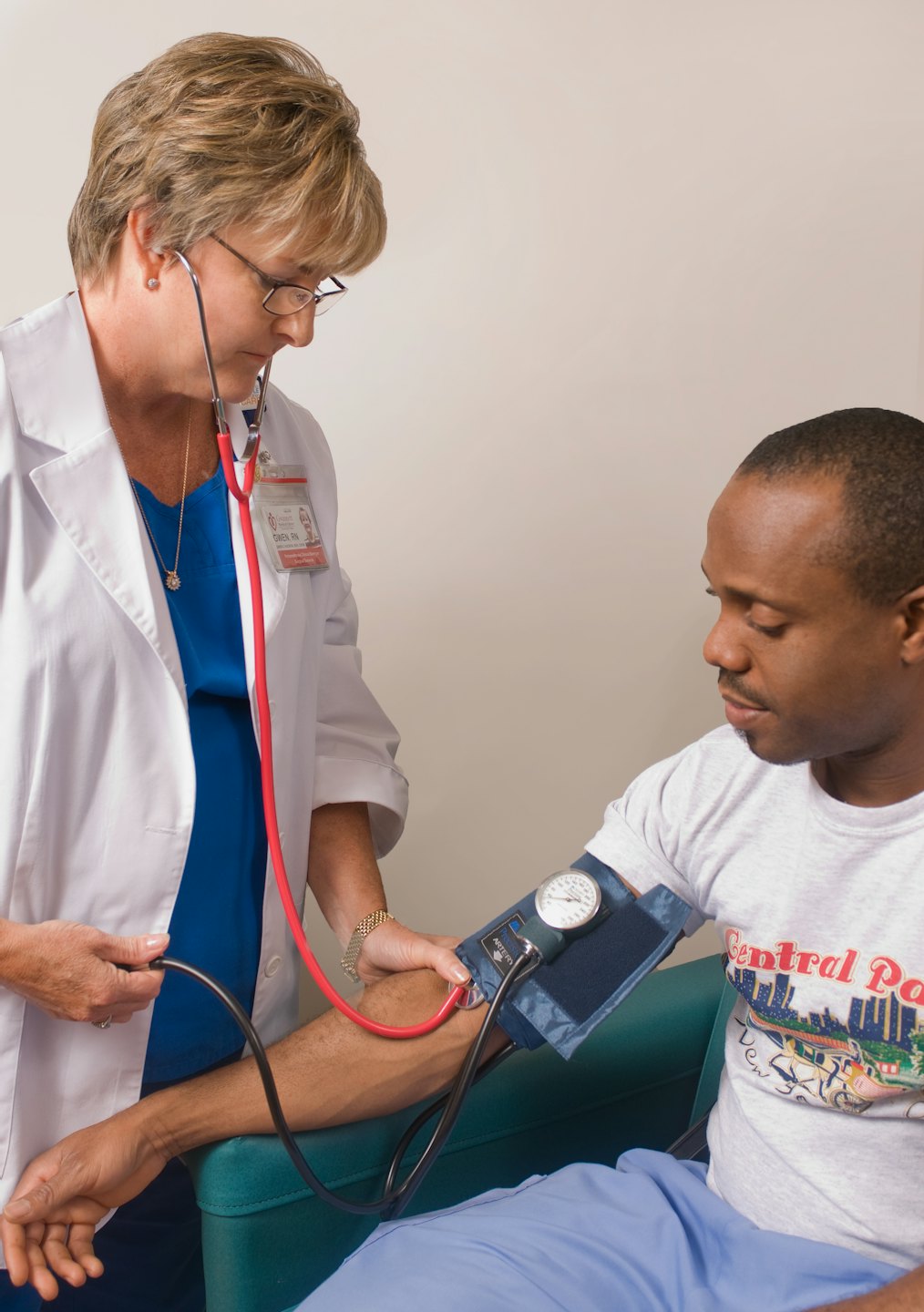 Nurse takes a patient's blood pressure in a medical room.